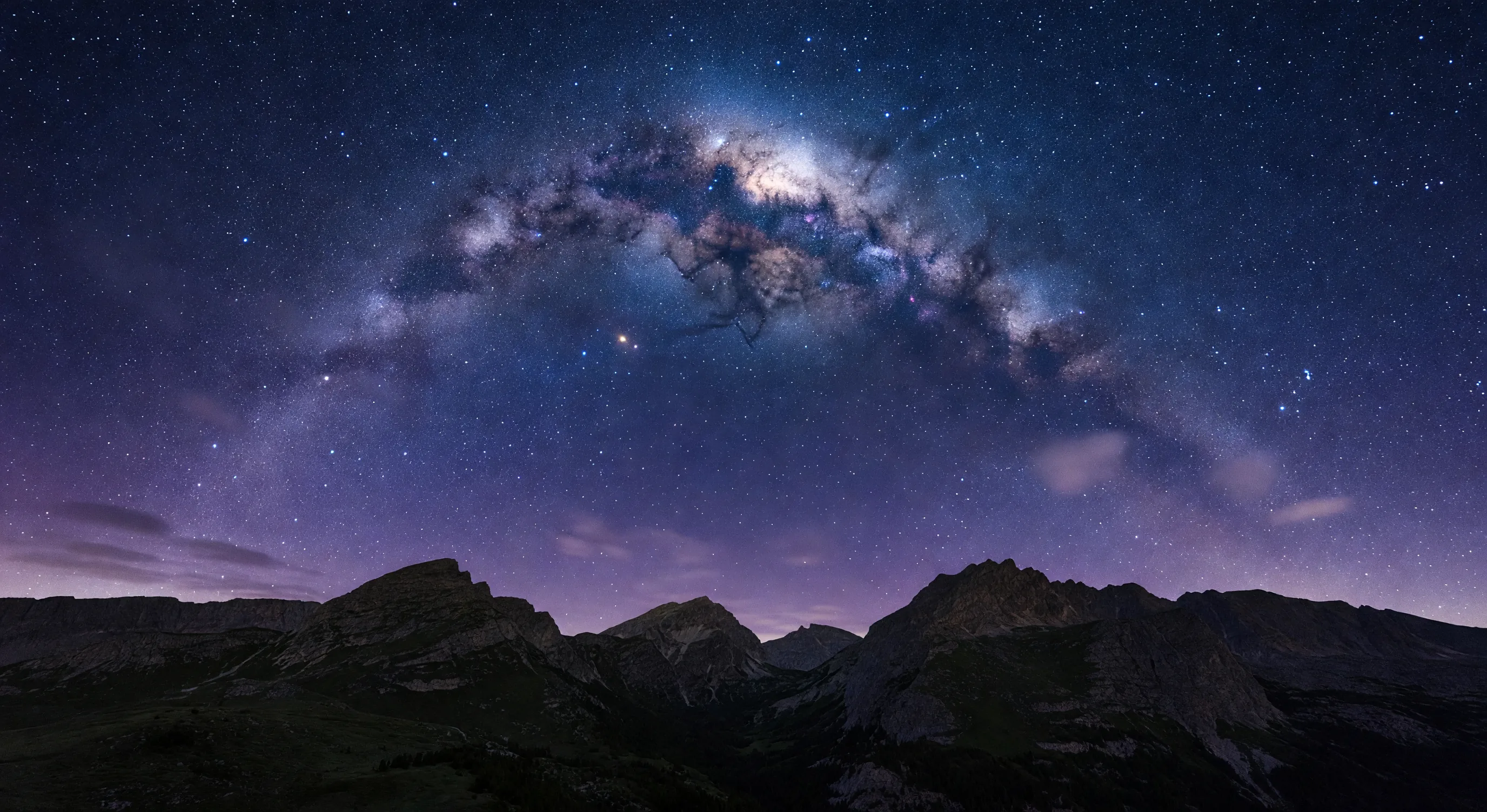 Dramatic view of the Milky Way arching across the night sky over mountains